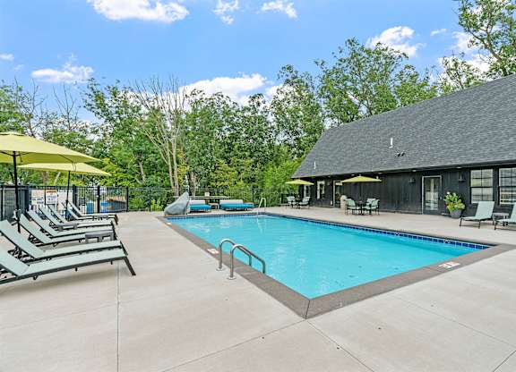 A pool with sun loungers and a building in the background.
