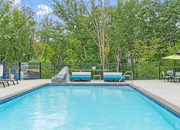 A swimming pool surrounded by trees and a fence.