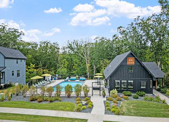 A black house with a pool in front of it.
