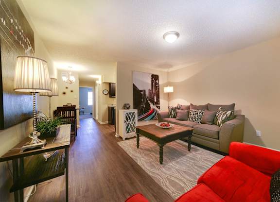 A living room with a red couch and a wooden coffee table.