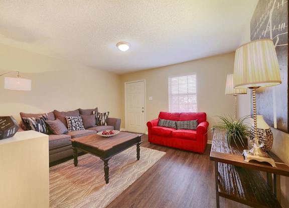 A living room with a red couch and a wooden coffee table.