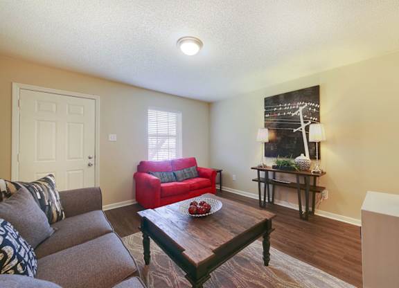 A living room with a red couch and a wooden coffee table.