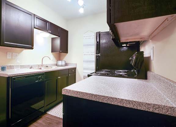 A kitchen with black cabinets and a black oven.