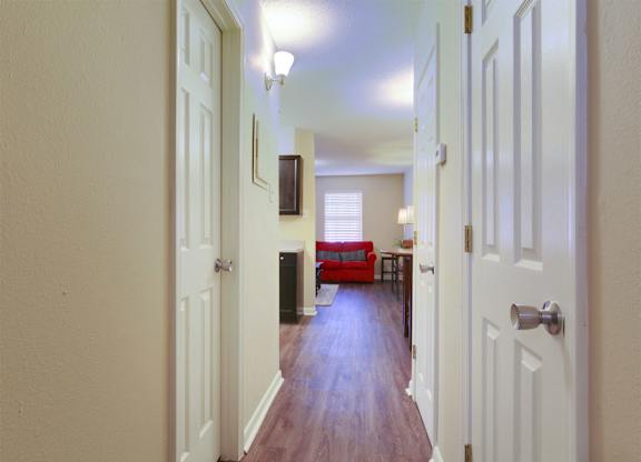 A hallway with white doors and a red couch in the background.