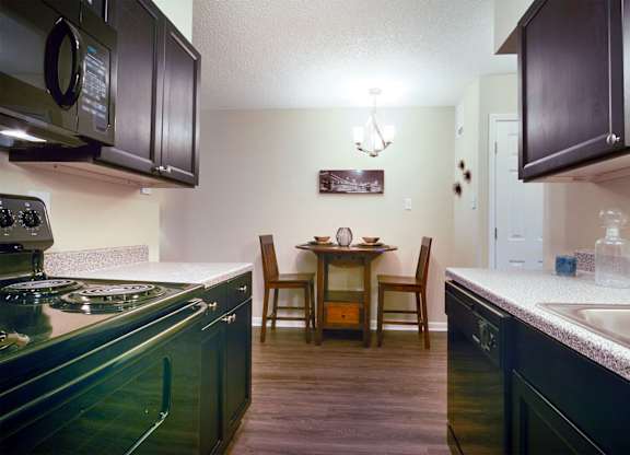 A kitchen with dark cabinets and a dining table with chairs.