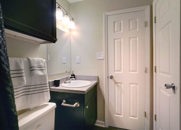 A bathroom with a white door and a green vanity.