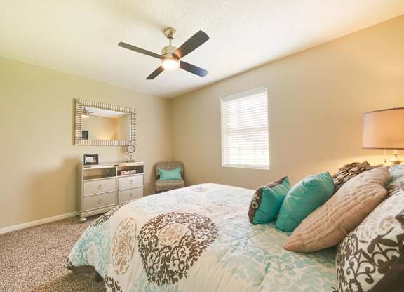 A bedroom with a bed, dresser, mirror, and window.