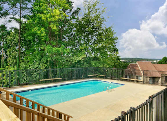 A pool surrounded by a fence and trees.