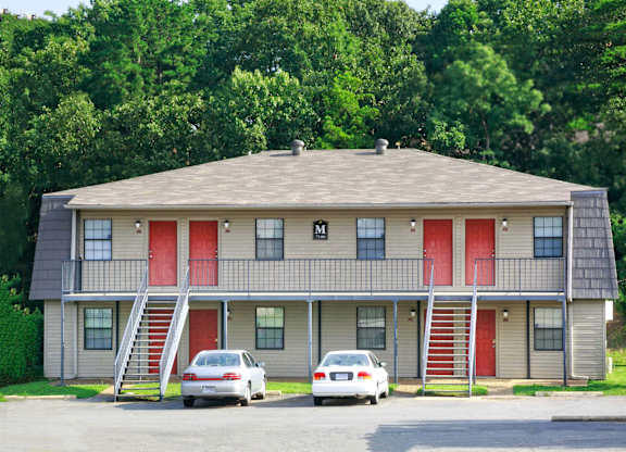 A building with red doors and two cars parked in front.