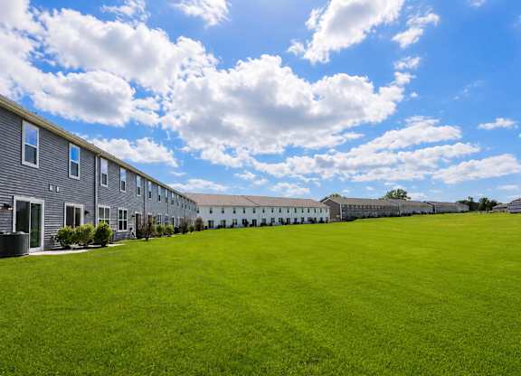 A row of houses with a green lawn in front.