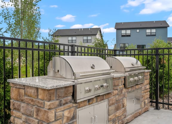 an outdoor kitchen with two bbq grills and a granite countertop