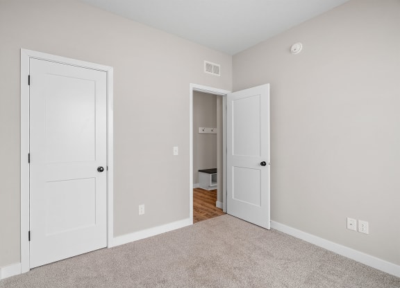 a bedroom with two doors and a carpeted floor