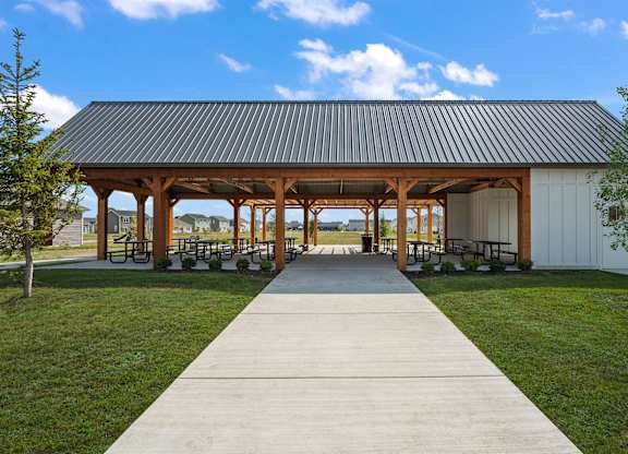 A pavement leads to a pavilion with a white building and a black roof.