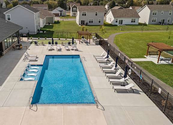 A large swimming pool surrounded by lounge chairs and a pavilion.