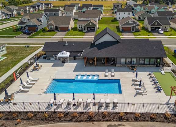 A swimming pool surrounded by lounge chairs and umbrellas in a residential area.