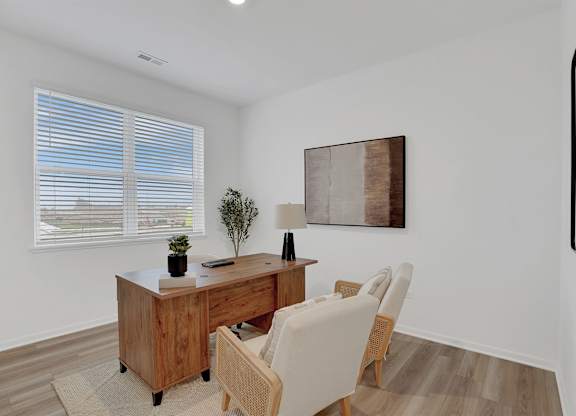 A room with a desk and chair in front of a window with blinds.