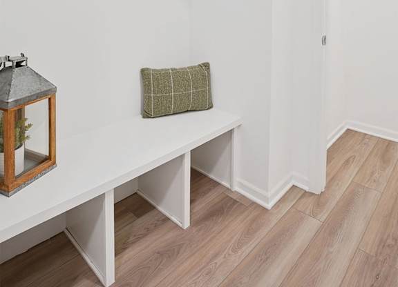 A white bench with a green pillow and a lantern on it.