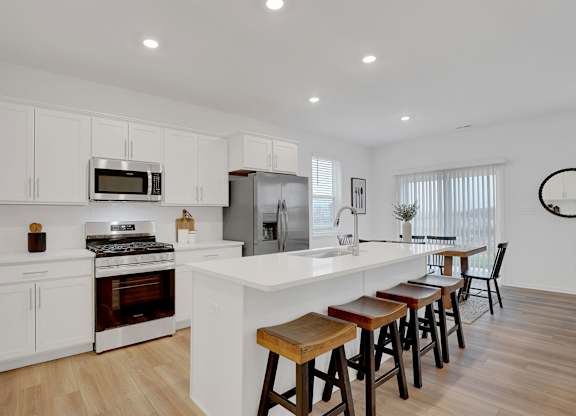 A modern kitchen with white cabinets and a wooden island.