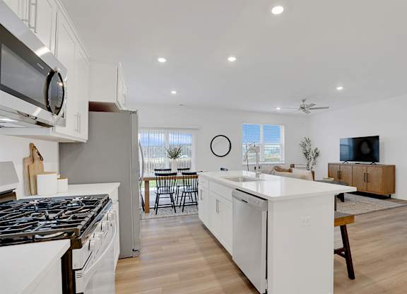 A modern kitchen with white cabinets and a black stove top.