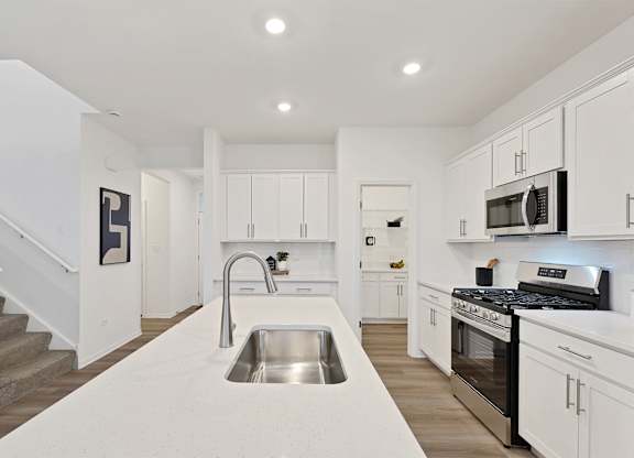 A modern kitchen with white cabinets and stainless steel appliances.