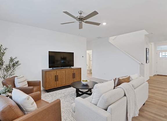 A living room with a brown leather chair, a white couch, and a wooden cabinet.