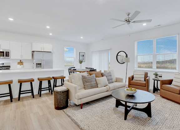 A living room with a white couch, a coffee table, and a ceiling fan.