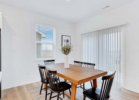 A dining room with a wooden table and chairs.