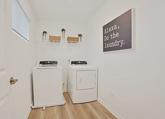 A laundry room with a sign that says "Alexa, do the laundry.".