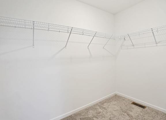 A white wall with a wire shelf and a carpeted floor.