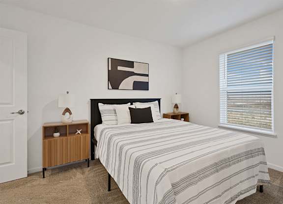 A bedroom with a bed, nightstand, and lamp.