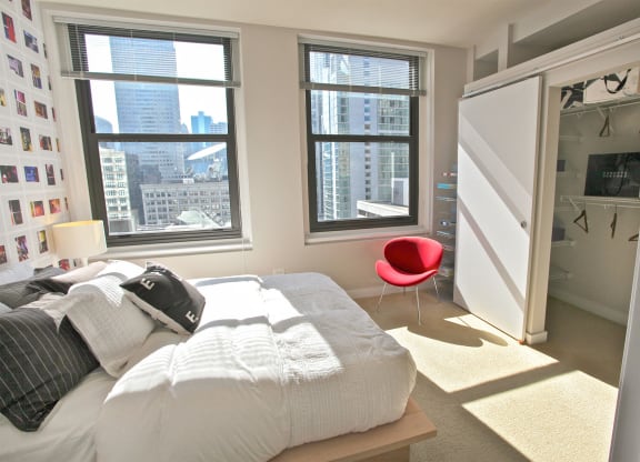 a bedroom with a bed and a closet and three windows