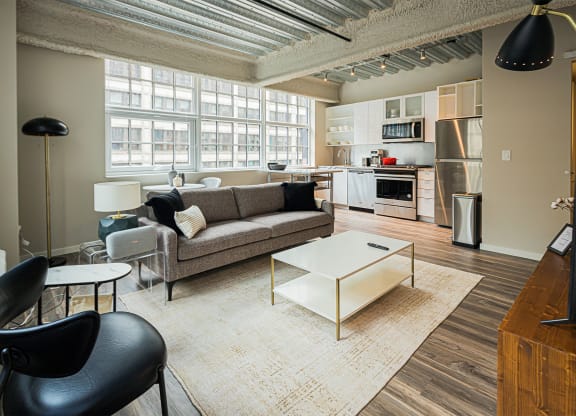 a living room with a couch and a coffee table    and a kitchen