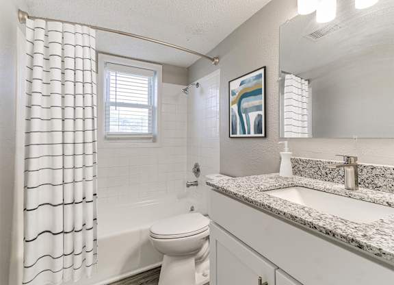 A bathroom with a toilet, sink, and shower curtain.