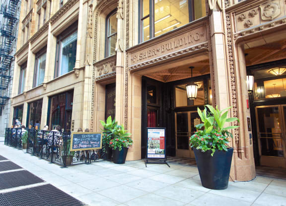 the outside of a building with potted plants on the sidewalk