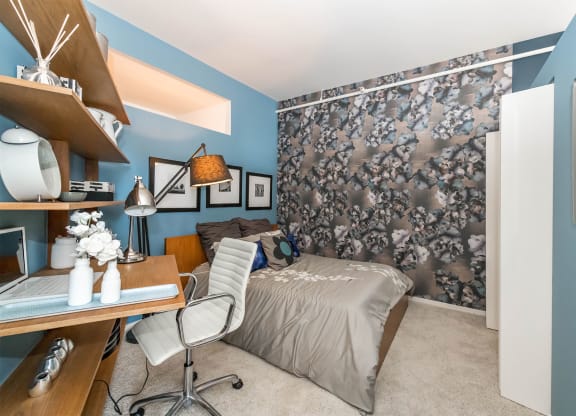 a bedroom with blue walls and a bed and a desk