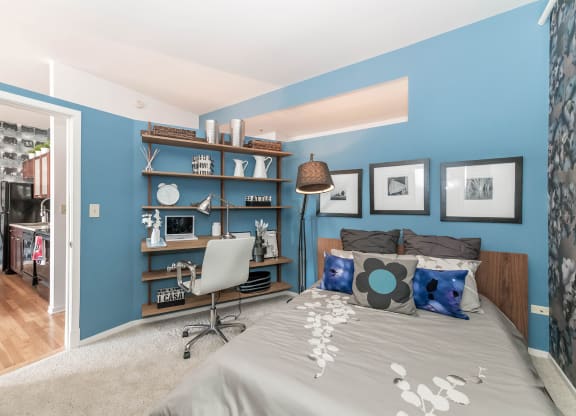 a bedroom with a bed and a blue wall and a desk