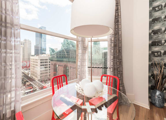 a dining room with a large window and a table with red chairs