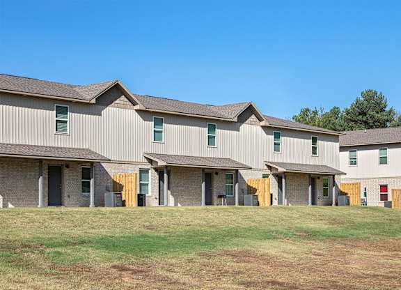 A row of houses with a grassy field in front.