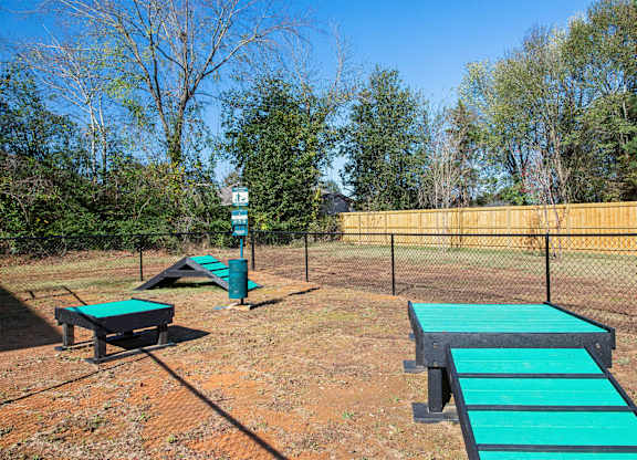 A playground with a green slide and a wooden fence.