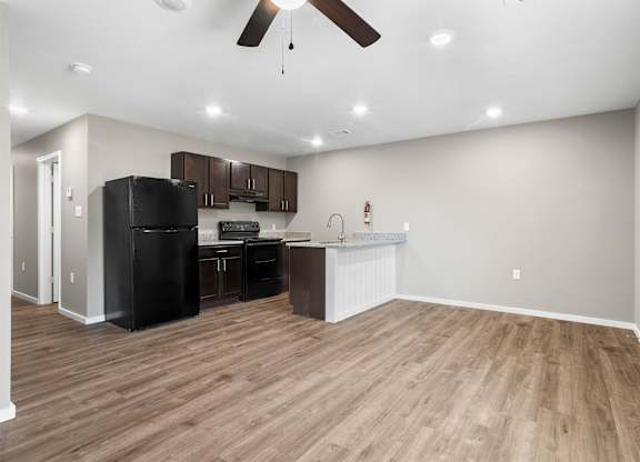 A kitchen with a black fridge and wooden floors.