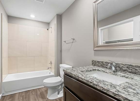 A white toilet sits next to a bathtub in a bathroom.
