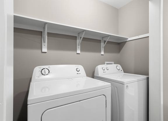 Two white front loading washing machines in a laundry room.