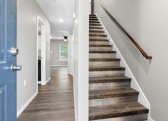 A staircase with wooden steps and a blue door on the left.