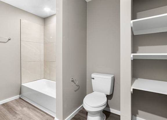 A white toilet sits next to a bathtub in a small bathroom.