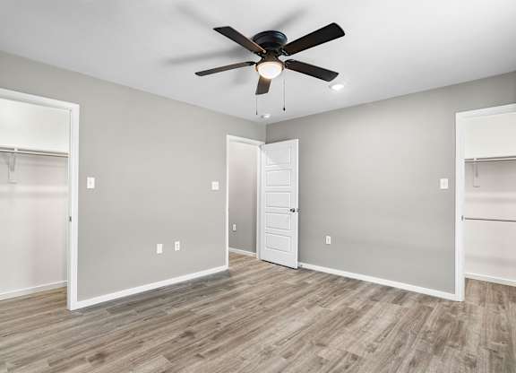 A room with a ceiling fan and wooden flooring.