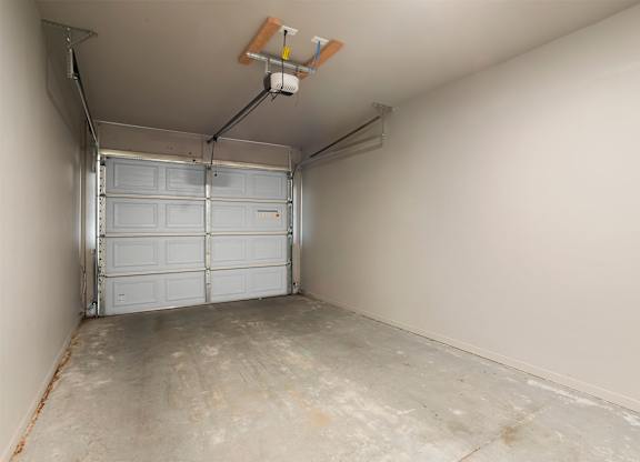 A garage with a white door and a concrete floor.