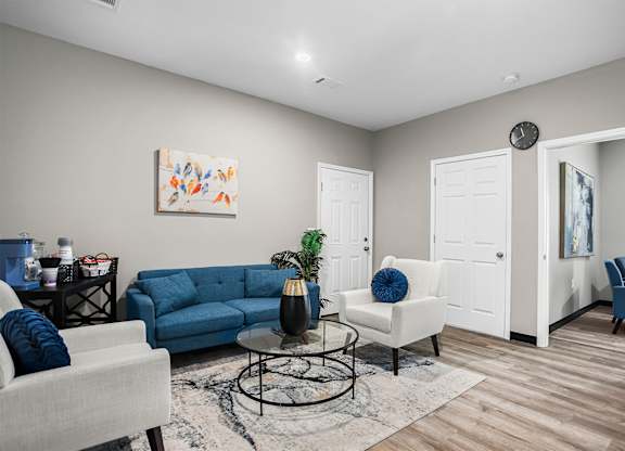 A living room with a blue couch and a white chair.