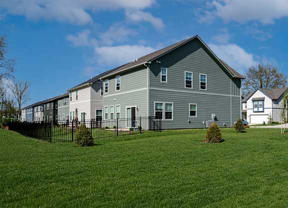 A grey house with a black fence in front of it.