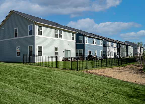 A row of houses with a black fence in front.