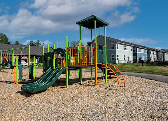 A playground with a green slide and orange and yellow play equipment.